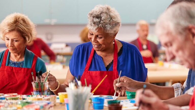 smiling seniors engaging in art therapy class